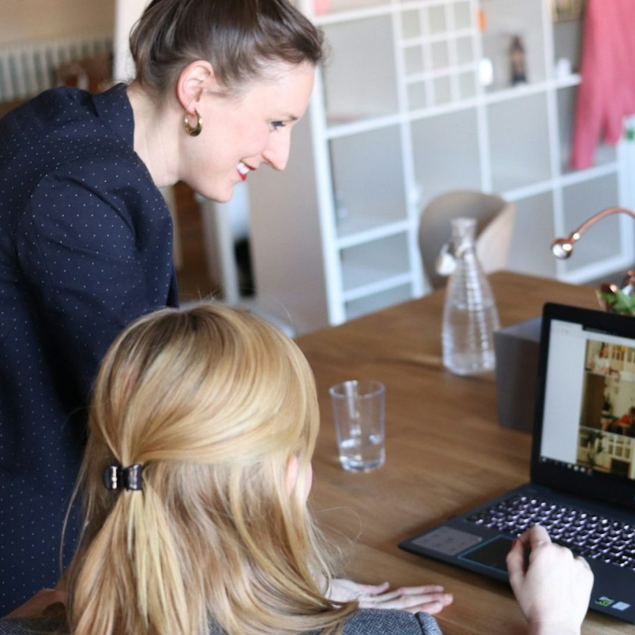 Eine Frau am Laptop bekommt Unterstützung von einer Bildungsbegleiterin