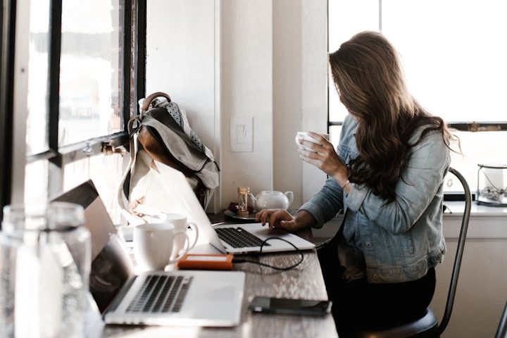 Frau arbeitet entspannt mit Kaffee in der Hand ansynchrone am Laptop